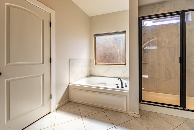 bathroom with a stall shower, a garden tub, baseboards, and tile patterned floors