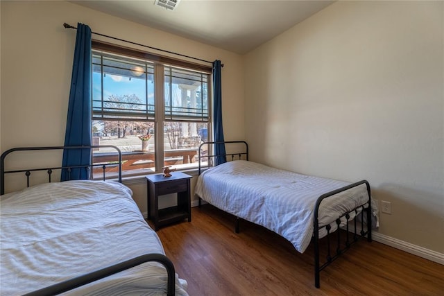 bedroom with visible vents, baseboards, and wood finished floors