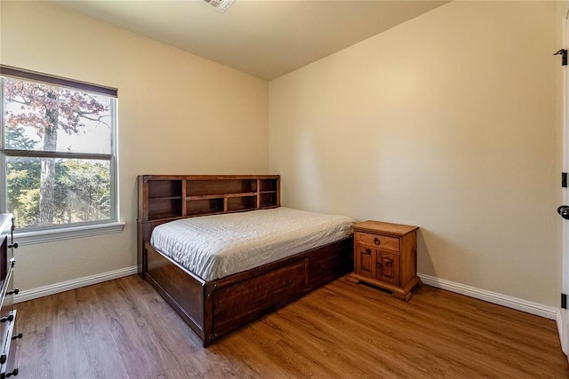 bedroom featuring wood finished floors, visible vents, and baseboards