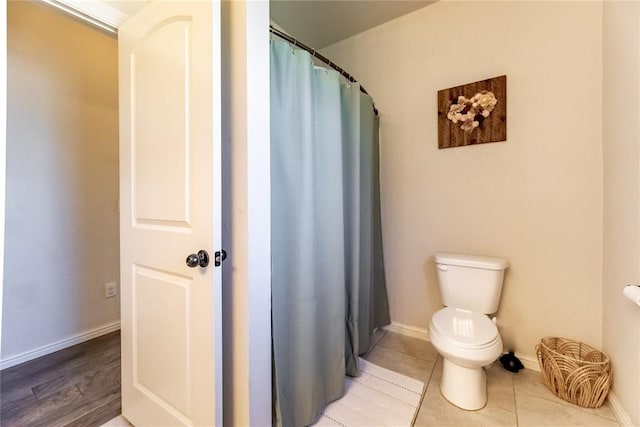 bathroom featuring a shower with curtain, tile patterned flooring, toilet, and baseboards