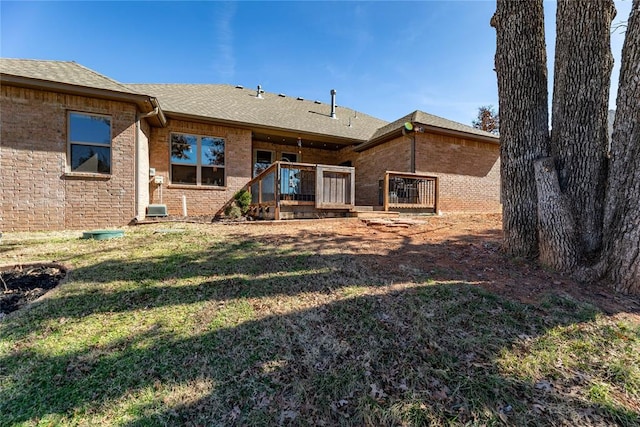 back of house with a yard, brick siding, and a shingled roof