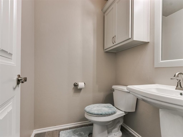 half bath featuring toilet and baseboards