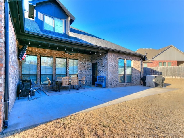 rear view of house with ceiling fan, a patio, brick siding, and fence