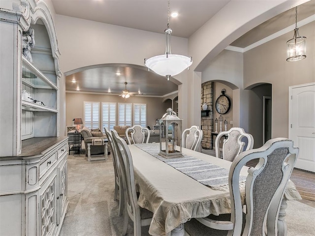 dining area featuring light carpet, ornamental molding, and a ceiling fan