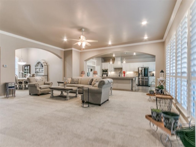 living room featuring light carpet, ornamental molding, a ceiling fan, and recessed lighting