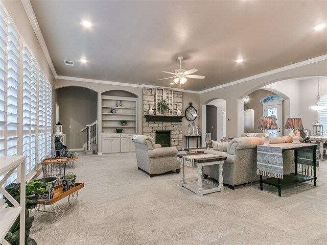 living area with built in shelves, ornamental molding, light colored carpet, and a stone fireplace