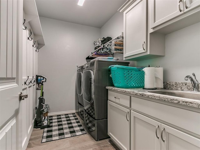 laundry area featuring a sink, baseboards, washer and dryer, cabinet space, and wood tiled floor