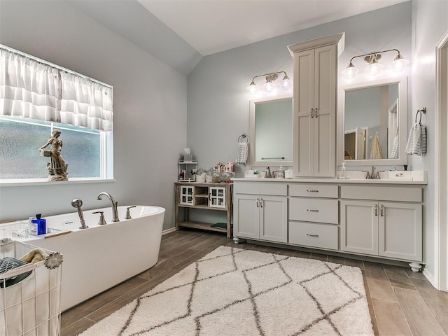 full bath featuring lofted ceiling, double vanity, wood finish floors, and a sink