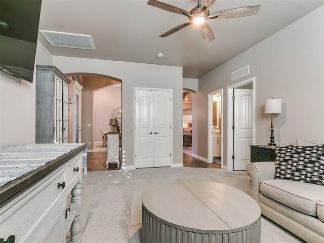 interior space featuring arched walkways, visible vents, ceiling fan, and light carpet