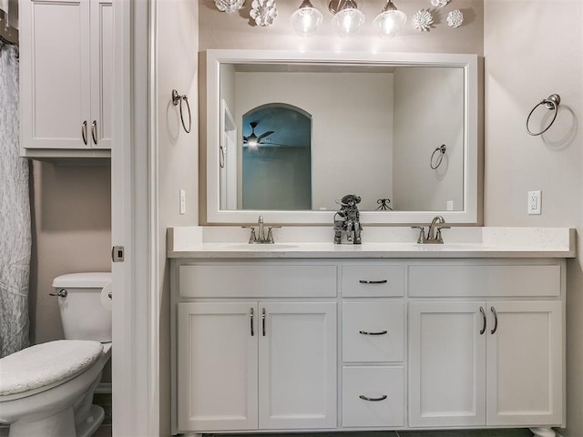 bathroom with double vanity, a sink, and toilet