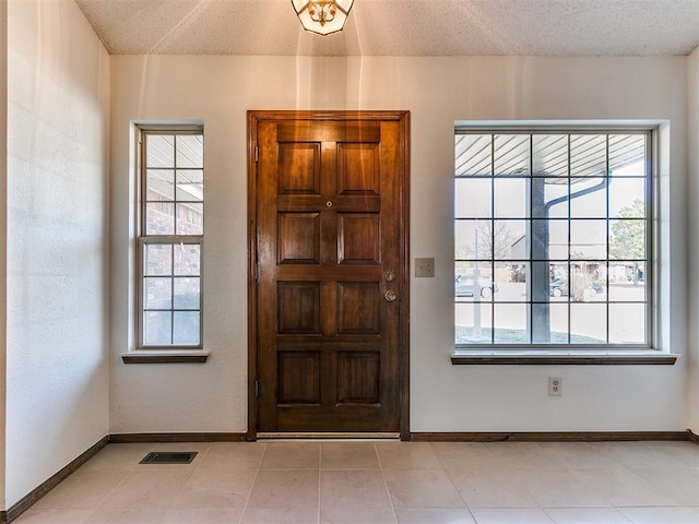 entryway featuring baseboards, visible vents, and a textured ceiling