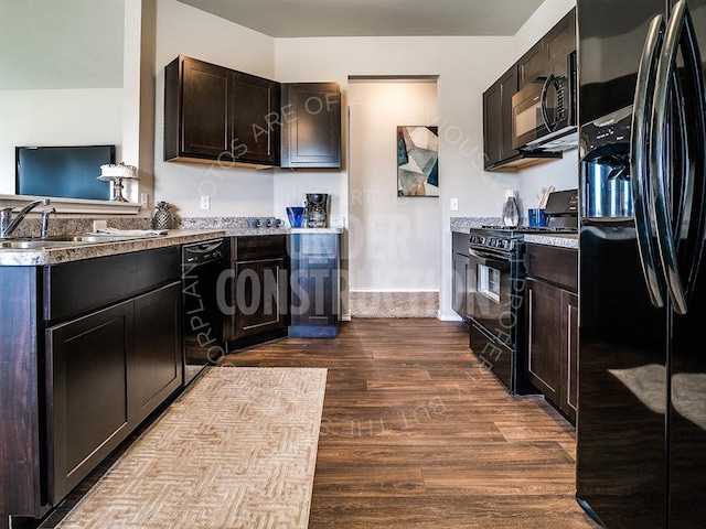 kitchen with baseboards, wood finished floors, light countertops, dark brown cabinets, and black appliances