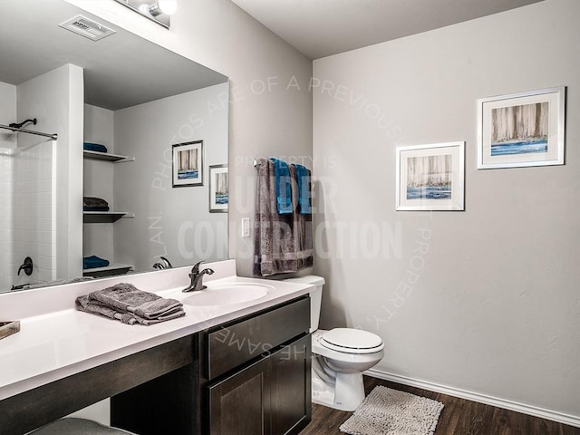 bathroom with toilet, vanity, wood finished floors, and visible vents