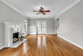 unfurnished living room with ornamental molding, a fireplace with raised hearth, baseboards, and wood finished floors