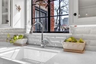 room details with light countertops, a sink, glass insert cabinets, and white cabinets