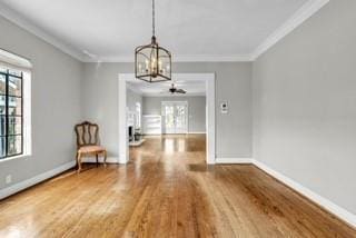 unfurnished dining area featuring baseboards, wood finished floors, and crown molding