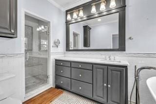 bathroom with a tub to relax in, crown molding, wainscoting, vanity, and wood finished floors