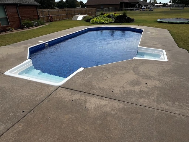 view of swimming pool featuring a lawn and fence