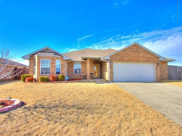 single story home with a garage, driveway, brick siding, and fence