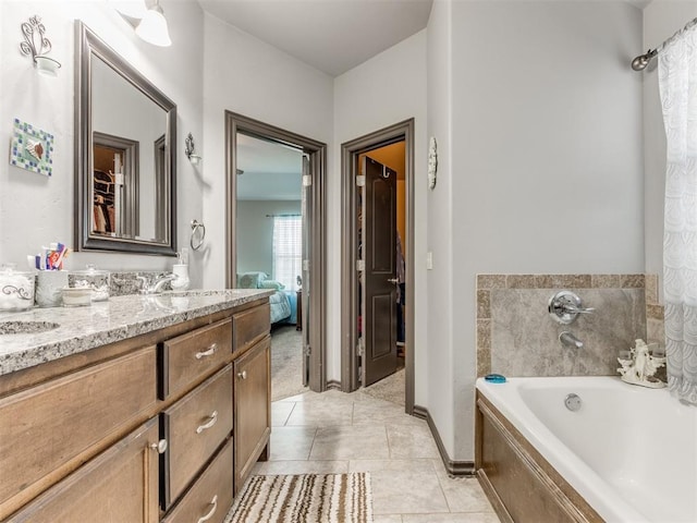 ensuite bathroom with tile patterned flooring, connected bathroom, vanity, baseboards, and a bath