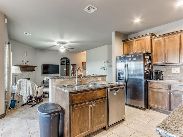 kitchen with a center island with sink, visible vents, appliances with stainless steel finishes, a fireplace, and a sink