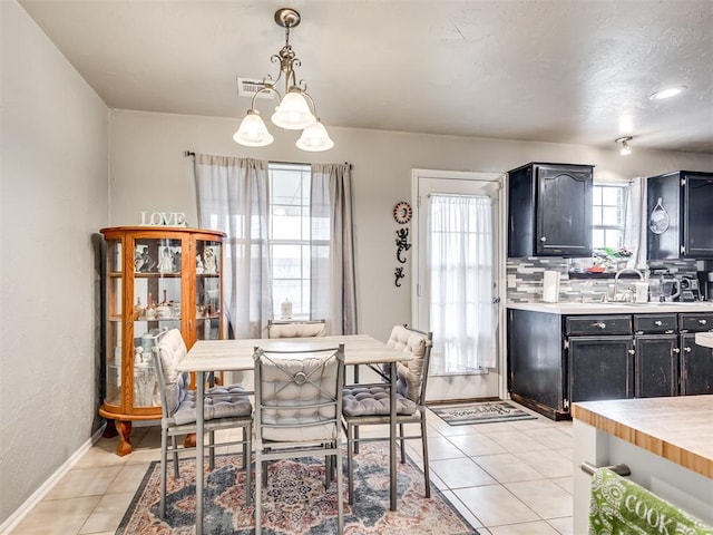 dining space with a notable chandelier, light tile patterned flooring, visible vents, and baseboards