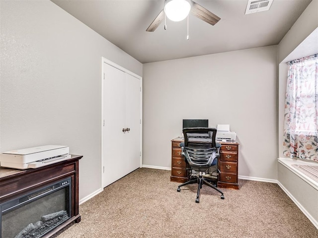 home office with light colored carpet, ceiling fan, visible vents, and baseboards