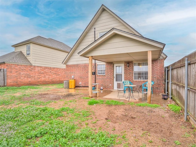 back of property featuring brick siding, a patio, a fenced backyard, and central air condition unit