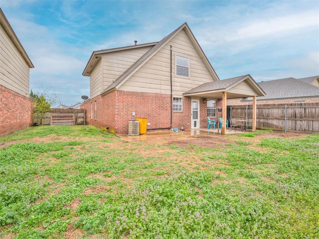 rear view of house featuring a yard, a fenced backyard, a patio area, and brick siding