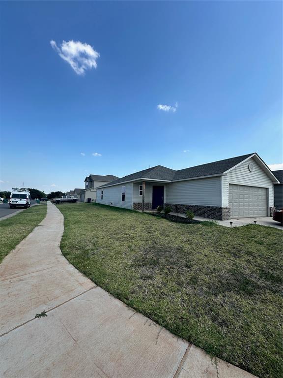 view of front of property with a garage, driveway, stone siding, roof with shingles, and a front lawn