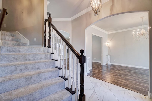 stairs with arched walkways, marble finish floor, crown molding, an inviting chandelier, and baseboards