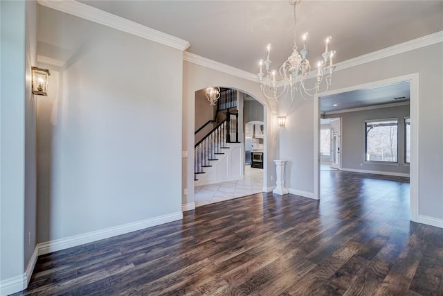 interior space with arched walkways, ornamental molding, wood finished floors, stairs, and a notable chandelier