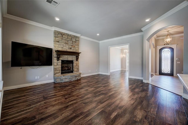 unfurnished living room featuring arched walkways, dark wood finished floors, a fireplace, visible vents, and baseboards