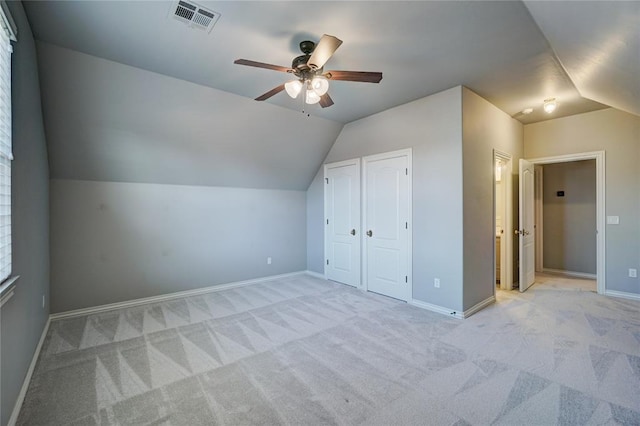 additional living space featuring baseboards, visible vents, vaulted ceiling, and light colored carpet