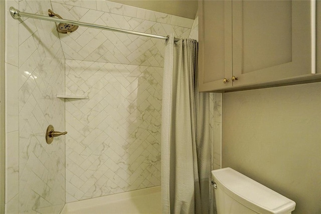 full bathroom featuring a tile shower and toilet