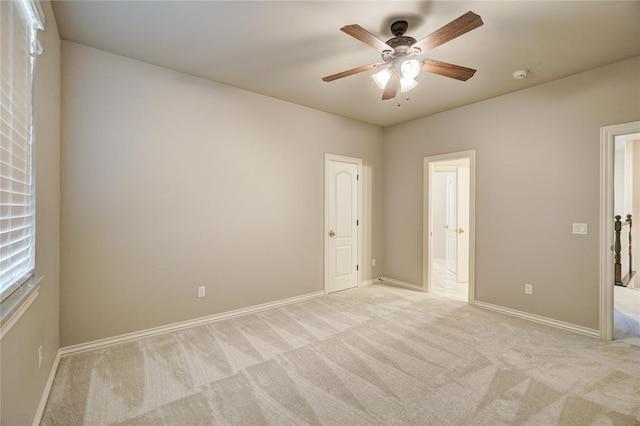 spare room featuring light carpet, ceiling fan, and baseboards