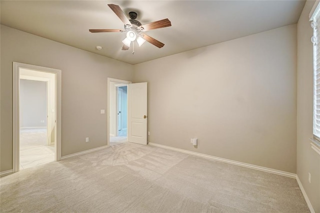 empty room with light colored carpet, ceiling fan, and baseboards