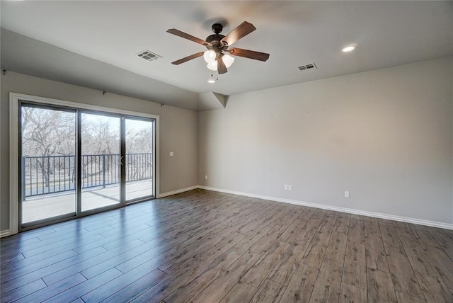 spare room with wood finished floors, visible vents, and baseboards