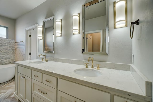 full bath featuring double vanity, a freestanding bath, tile walls, and a sink