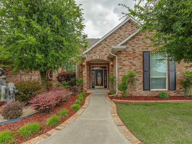 16632 Parkhurst Rd, Edmond, OK 73012 - doorway to property featuring brick siding and a lawn