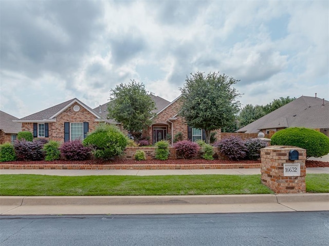 16632 Parkhurst Rd, Edmond, OK 73012 - view of front of home featuring brick siding, a front yard, and roof with shingles