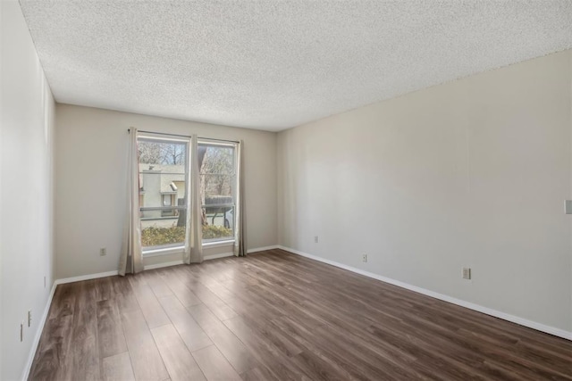 spare room with dark wood-style floors, a textured ceiling, and baseboards