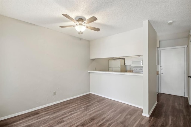 unfurnished room with baseboards, a textured ceiling, a ceiling fan, and dark wood-type flooring