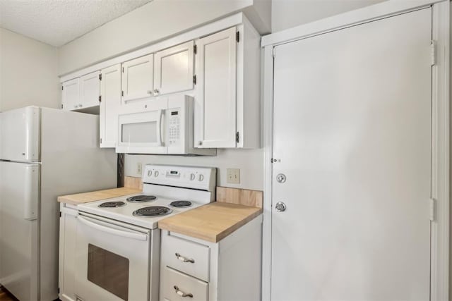 kitchen with white appliances, white cabinets, a textured ceiling, and wood counters