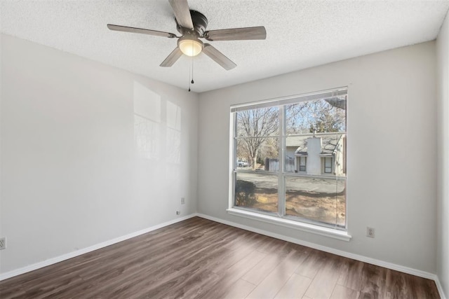 empty room with dark wood-style floors, ceiling fan, a textured ceiling, and baseboards