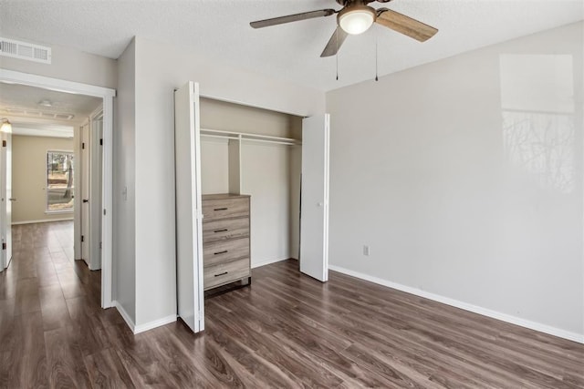 unfurnished bedroom with dark wood-style flooring, a closet, visible vents, and baseboards