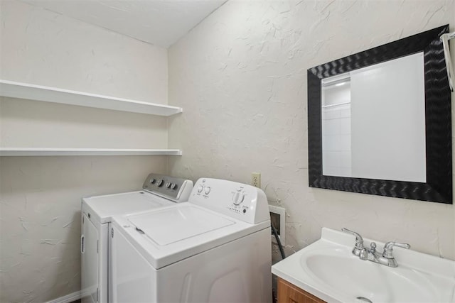 laundry area featuring laundry area, washing machine and dryer, a sink, and a textured wall