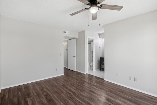 empty room with a textured ceiling, wood finished floors, visible vents, and baseboards