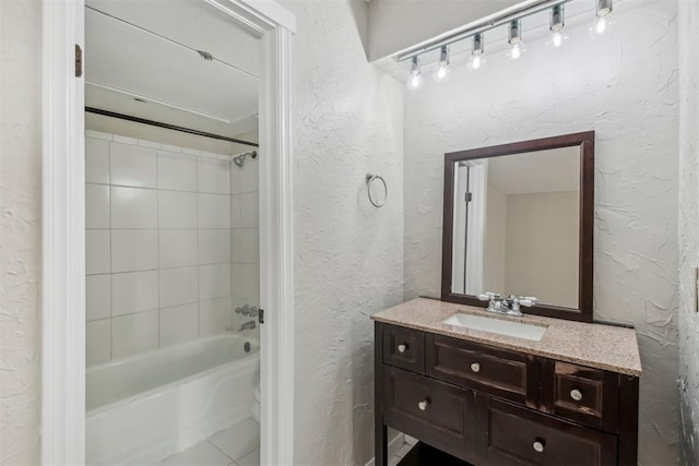 bathroom with washtub / shower combination, a textured wall, and vanity