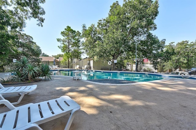 community pool with a patio and fence